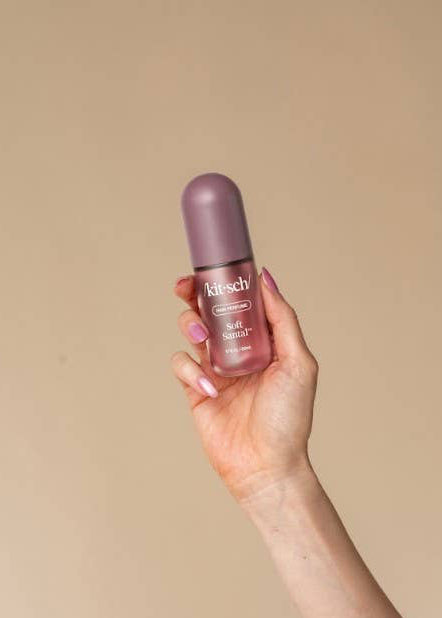 A hand holding a small bottle of bitsch Beauty Glow Serum against a solid beige background.
